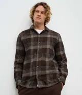 Camisa de manga larga confeccionada en franela de algodón, con cuello bowling y cierre frontal de botones. Presenta un diseño de estampado a cuadros en tonos marrones y beige, con un corte regular tradicional.