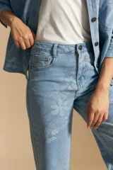 Pantalón de jean de tiro alto, corte ancho y pierna recta, en tono celeste claro con estampado jacquard de flores.
