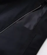 Campera boxy de poliéster color beige, con cuello inglés, cierre frontal de cremallera, mangas largas con elástico en los puños, bolsillos laterales y detalles de recortes.