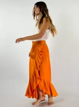 Pollera larga color naranja, de corte recto y con volados en diagonal en el frente.