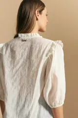 Camisa blanca de manga corta abullonada con terminación elastizada y cuello con leve frunce. Presenta una estampa floral integral.