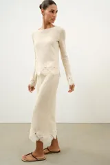 Falda midi de tejido rústico en color beige, con tiro medio, cintura elástica y detalle de aplicación de crochet en el bajo.