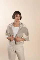 Chaleco sin mangas de tejido de lana fina sin teñir, con diseño circular y bloques de color beige y marrón. Presenta un cuello amplio y solapa que permite usarlo como chaleco largo o capa corta.