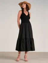 Vestido maxi combinado negro de la marca Elan, con torso de punto acanalado con escote en V pronunciado y breteles anchos. Cuenta con corte a la cintura y falda larga fluida con volumen, bolsillos laterales y volante fruncido en el ruedo.
