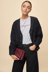 Sobrecamisa de jean azul oscuro, de calce relajado, escote en V, bolsillos delanteros aplicados, cierre frontal con botones metálicos y pespuntes en contraste.