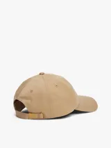 Gorra de béisbol de algodón en color beige, con diseño clásico de cinco paneles, ojales de ventilación y visera curva. Presenta un parche bordado con el logo de Tommy Jeans en la parte frontal y cuenta con una hebilla metálica ajustable en la parte trasera.