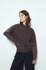 Buzo canguro color marrón oscuro con efecto lavado, calce relajado, capucha integrada, bolsillo frontal tipo canguro y terminaciones clásicas en puños y ruedo.