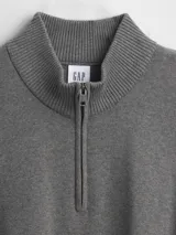 Buzo de tejido de punto color negro, con cuello alto y cierre frontal parcial. Presenta puños y ruedo acanalados.