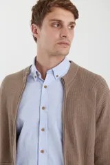 Cardigan de tejido de punto con cierre frontal completo, cuello redondo y bolsillos laterales. Presenta un diseño de textura acanalada y puños elásticos.