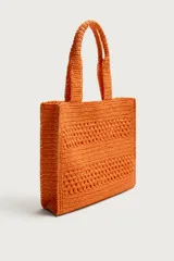 Bolso tipo shopper de color naranja con acabado trenzado y diseño estructurado. Cuenta con compartimento principal y dos asas cortas de mano.