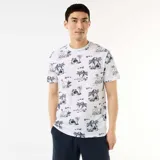 Remera blanca con estampado tropical de palmeras y paisajes en azul oscuro, de manga corta y cuello redondo.