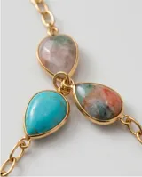 Collar de cadena fina con baño de oro, adornado con piedras naturales de diversos colores y formas ovaladas distribuidas a lo largo de la pieza.