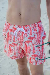 Short de baño blanco con estampado de hojas y flores rojas, cintura elástica con cordón blanco.