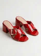 Sandalia de taco ancho color dorado, confeccionada en cuero vacuno, con diseño de tiras cruzadas y hebilla metálica decorativa.