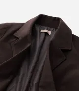 Sobretodo de corte largo y estructura encorpada, color marrón chocolate. Presenta cuello con solapa, cierre frontal de doble abotonadura y bolsillos laterales con solapa.