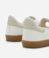 Championes estilo chutera de mujer, con diseño de punta redonda y cierre de velcro. Presenta una combinación de colores blanco, beige y negro con recortes contrastantes y suela plana color caramelo.