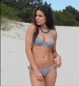 Conjunto de bikini a rayas verticales color lila y verde. El corpiño tiene aro, breteles ajustables y gancho metálico. La bombacha es tipo tanga con tiras laterales ajustables.