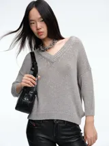 Sweater de punto con brillo, de corte relajado y escote en V. Presenta hombros caídos y mangas largas con puños acanalados.