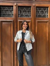 Chaqueta plateada metalizada con cuello camisero, cierre frontal con botones, bolsillos de parche en el pecho y corte recto.