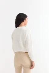 Sweater de punto con textura tipo waffle, color blanco, de corte clásico con cuello redondo y mangas largas.