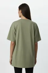 Remera de algodón de manga corta y cuello redondo, con diseño holgado y estampado frontal con motivos florales y texto.