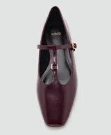 Zapato tipo bailarina con diseño de pulsera en T, confeccionado en cuero charolado color bordó, con punta fina y cierre de hebilla metálica dorada.