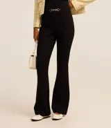 Pantalón flare negro de punto roma con detalle metálico en la cintura y cierre delantero.