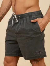 Short de baño color beige, de corte volley, con cintura elástica y cordón ajustable. Presenta un pequeño logo bordado en la parte inferior de la pierna izquierda.