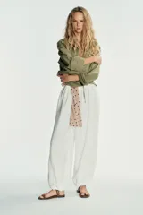 Pantalón blanco de tejido fluido, tiro medio con cintura elástica y bajo abullonado.