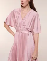 Vestido maxi de satén color rosado, con escote en V cruzado, mangas cortas amplias, cintura elastizada con lazo de ajuste y falda plisada con forro interno.