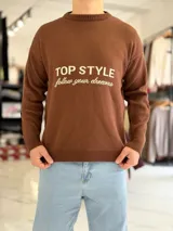 Sweater de punto color beige con cuello redondo, manga larga y diseño estampado en el pecho con las frases "TOP STYLE" y "follow your dreams" en color marrón.