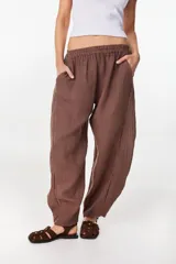 Pantalón de lino marrón, de corte relajado y estilo fluido, con cintura elástica y bolsillos laterales.
