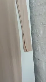 Top de lycra color beige, con cuello alto y mangas largas. Presenta un corte asimétrico en la parte inferior.