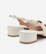 Zapato de tacón con textura croco, color blanco, modelo slingback, con puntera fina, taco bloque mediano y cierre por hebilla.