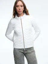 Campera acolchada ligera color blanco, con diseño de costuras onduladas, cuello alto y cierre frontal de cremallera.