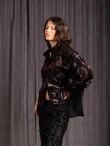 Camisa de manga larga con diseño de terciopelo estampado con motivos florales y paisley, combinada con paneles de tela transparente en la parte superior. Presenta cuello clásico, cierre frontal con botones y mangas abullonadas.