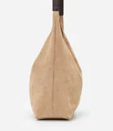 Cartera tipo hobo de gran tamaño confeccionada en material sintético efecto gamuza color tostado. Presenta una estructura flexible, asa única en tono contrastante y cierre mediante botón a presión.