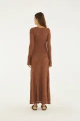 Vestido largo de punto color marrón, con diseño estampado de hojas en tono sutil, cuello redondo, mangas largas acampanadas y corte recto hasta los tobillos.