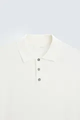 Polo de punto negro, manga corta, con cuello solapa y cierre frontal de tres botones. Presenta un calce regular y acabados en rib en mangas y ruedo.