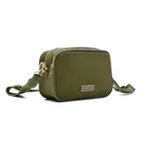 Bandolera rectangular color verde oliva, con correa ancha de tela regulable y logo metálico de la marca Korium en el frente.