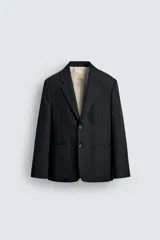 Blazer de corte relajado confeccionado en tejido de lana con estampado de raya diplomática. Presenta cuello con solapas de muesca, cierre frontal de dos botones, bolsillos de vivo en la cadera y abertura central en la espalda. Incluye forro interior a contraste.