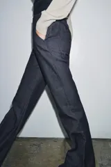 Jeans de tiro medio con corte flare y largo completo. Presenta bolsillos delanteros, cierre con cremallera, botón y ganchos metálicos.