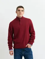 Sweater de punto color tostado, con cuello alto y cierre frontal parcial con botones. Diseño de manga larga con puños y ruedo acanalados.