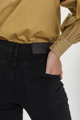 Pantalón jean negro de corte chupín, tiro alto y diseño ajustado, confeccionado en denim elástico con bolsillos traseros y presillas para cinto.