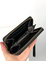 Mini billetera de cuero con textura efecto cocodrilo y cierre perimetral. Presenta un parche central con el logo de la marca grabado.