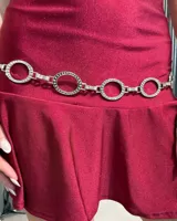 Cinturón de cadena plateado compuesto por eslabones circulares decorados con pequeñas incrustaciones brillantes.