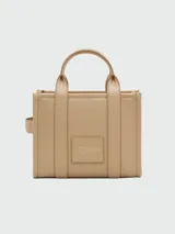 Cartera tipo tote de Marc Jacobs, confeccionada en cuero granulado color azul marino. Presenta el logo de la marca estampado en el frente, doble asa superior y correa ajustable y extraíble para llevar al hombro o cruzada.