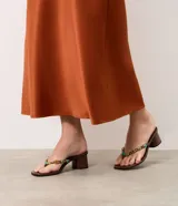 Sandalia de taco bloque Satinato, color marrón, estilo thong con tira de dedo decorada con apliques de piedras de resina y metales dorados.
