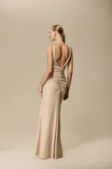 Vestido largo color beige con brillo, escote en V profundo, tirantes finos, nudo frontal en la cintura y abertura delantera en la falda.