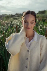 Cárdigan tejido en boucle color crudo, de corte holgado y mangas largas.